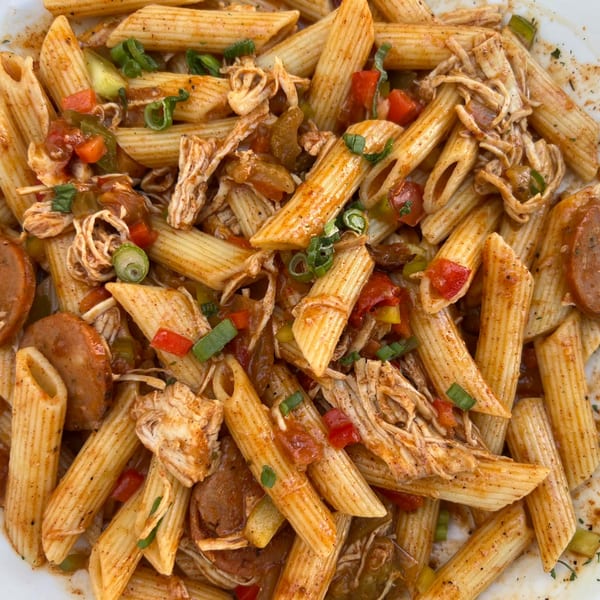 Cajun penne pasta with chicken, sausage, bell peppers, and green onions in a spicy sauce.