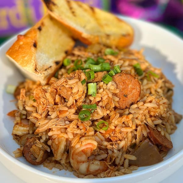 Jambalaya with shrimp, sausage, and chicken, topped with green onions and garlic bread.